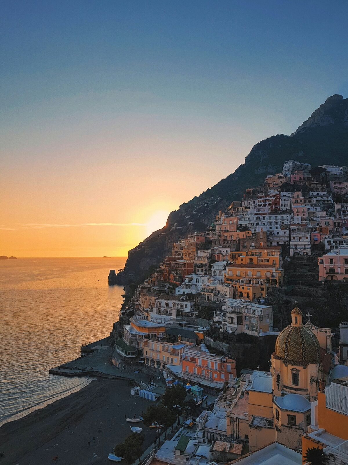 Positano at sunset, with the dome of Santa Maria Assunta above the Tyrrhenian Sea